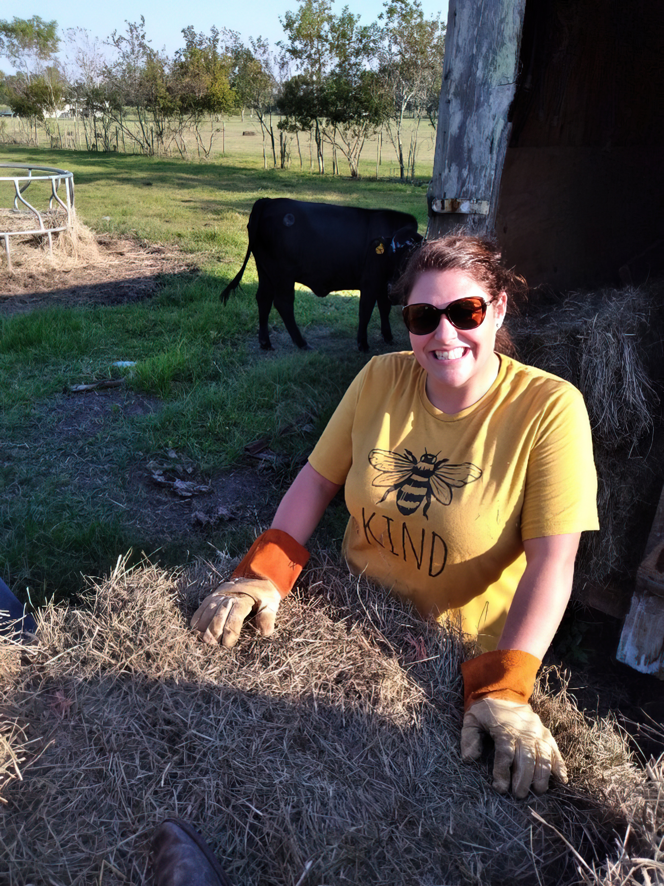 A woman stacks a bale of hay on a farm.